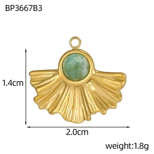 Detail view of a gold fan-shaped pendant with a green gemstone and size measurements