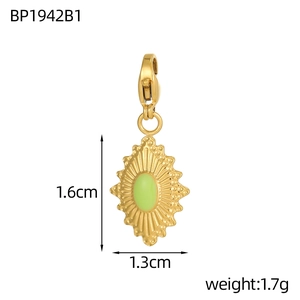 Detail view of gold stainless steel sunburst pendant with green enamel and lobster clasp