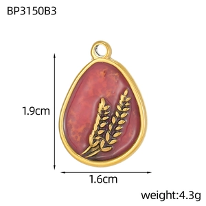 Macro view of teardrop pendant with gold wheat motif and red enamel measuring 1.9cm x 1.6cm