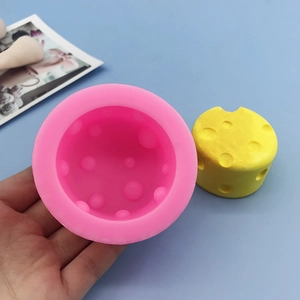 DIY cheese-shaped silicone mold and finished yellow candle shown in hand on blue background