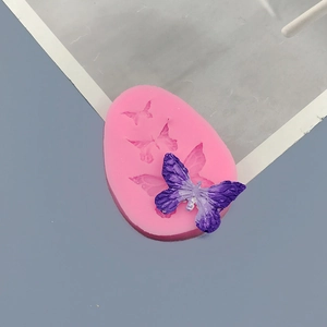 Pink silicone mold featuring three bow shapes with finished purple butterfly resin craft