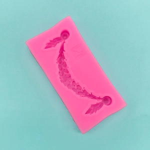 Macro detail of pink silicone cake mold with leaf tassels and food-grade icons
