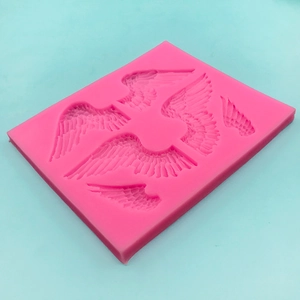 Pink silicone angel wings mold for fondant and resin art, sharp feather texture on blue base