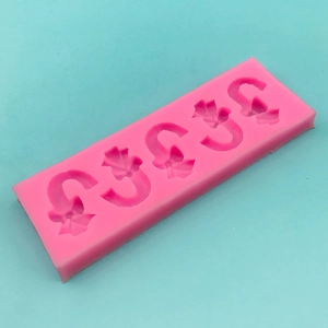 Pink silicone mold featuring four candy cane and leaf patterns for Christmas baking