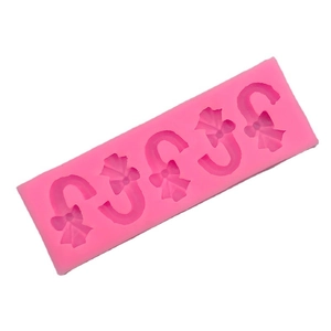 Pink silicone mold featuring four Christmas candy cane shapes with bows for baking cakes