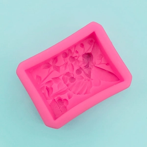 Macro view of pink silicone mold with detailed fairy girl and flower relief patterns