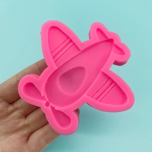 Pink silicone airplane mold for fondant and cake DIY held in hand on blue background