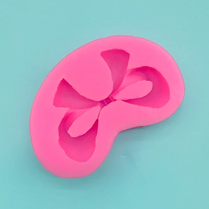 Detail view of pink bow-shaped silicone mold on a blue background for DIY baking cake
