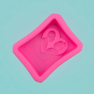 Detail of pink heart-shaped silicone mold with Happy Anniversary text and couple silhouette