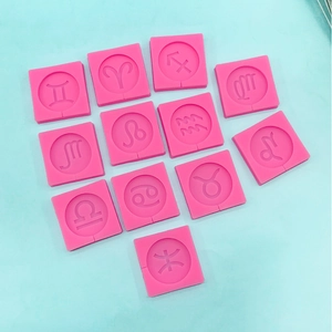 Detailed overhead view of 12 pink silicone molds featuring zodiac sign relief patterns