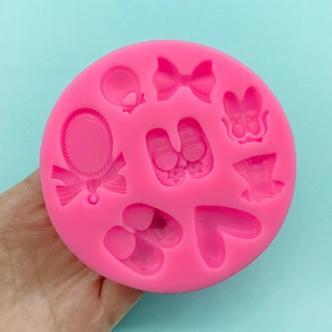 Pink silicone mold with bow, heart, and dress shapes for fondant and cake decoration
