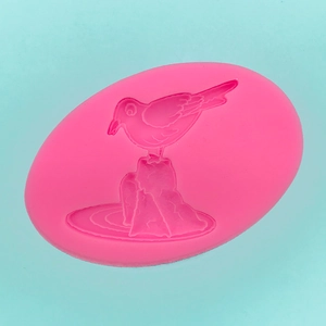 Macro view of pink silicone mold with 3D seagull and rock design for DIY baking