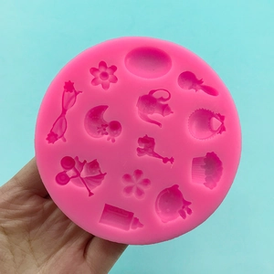 Pink silicone fondant mold with baby shower shapes like bottles and bears on blue background
