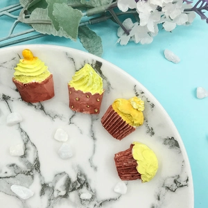 Set di quattro mini decorazioni per muffin gialli in resina su un piatto di marmo