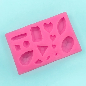 Dettaglio dello stampo in silicone rosa con cavità a forma di cuore e pietre preziose