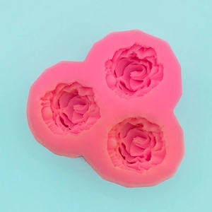 Detail view of the pink silicone mold featuring three intricate rose flower shapes for baking