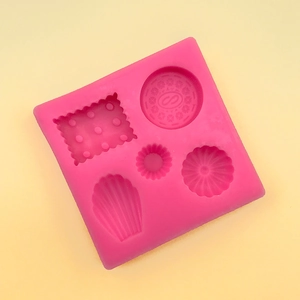 Detailed macro view of pink silicone mold with cookie, shell, and fondant shapes