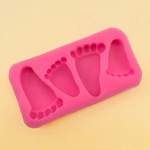 Detail showing pink silicone mold with four baby footprint cavities for DIY crafts