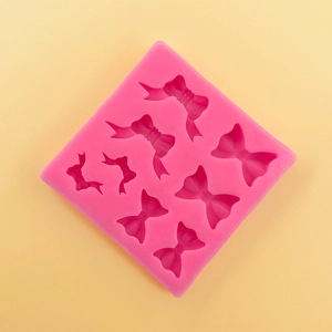 Detailed pink silicone mold featuring eight different bow tie shapes for cake decorating