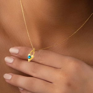 Golden heart-shaped sapphire lock pendant necklace worn on neck for women