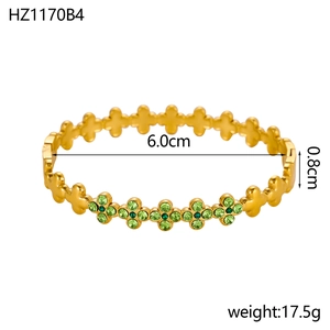 Gedetailleerde weergave van gouden klaverarmring met groene strassteentjes en maten