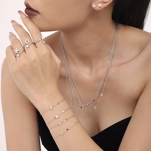 Detalle del conjunto de joyas y anillo con letra y circonitas brillantes en la modelo