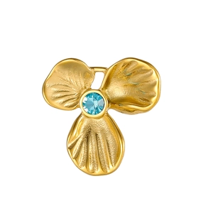 Macro di una chiusura a fiore placcata oro 18K con zircone blu e petali a trama radiale