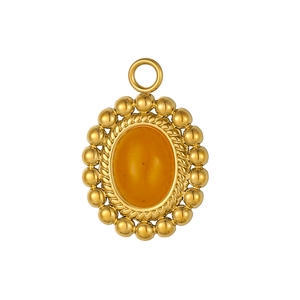 Dettaglio macro di un ciondolo ovale vintage con gemma gialla e bordo perlato oro