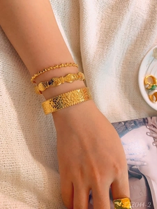 Close-up of gold plated stainless steel bracelet set with fish pattern and hammer texture