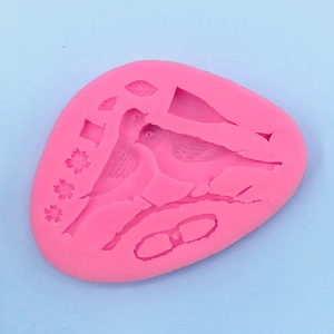 Pink silicone mold detail showing embossed magpie birds and floral leaf shapes for baking