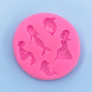Macro detail of pink silicone mold featuring mermaid and dolphin shapes for baking