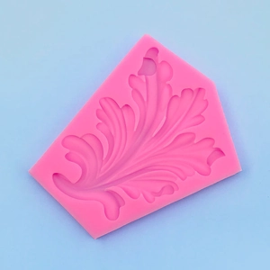 Close-up of pink silicone leaf mold with detailed baroque acanthus pattern on blue background