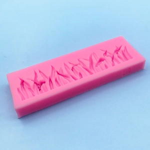 Pink silicone grass border mold for fondant and chocolate cake decoration on blue background
