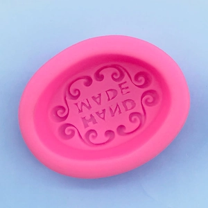 Detailed top view of pink silicone oval mold with decorative floral relief and handmade text