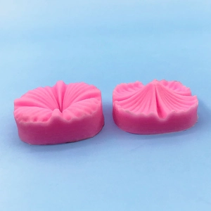 Nahaufnahme von zwei rosa Silikonformen für Kirschblütenblätter auf blauem Hintergrund