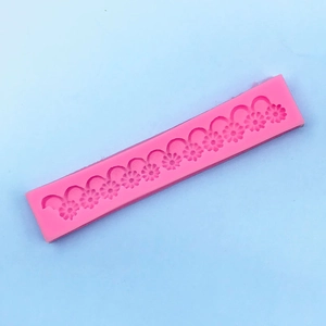 Detailed macro view of long pink silicone mold with daisy floral patterns for fondant cakes