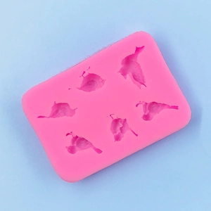 Close-up of pink silicone mold featuring six different cartoon bird shapes for baking