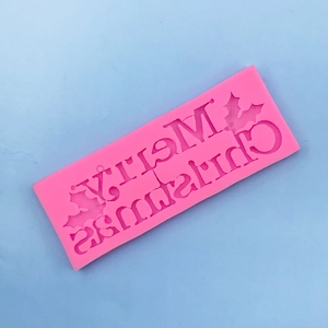 Close-up of pink silicone Merry Christmas letter mold with holly leaves for baking