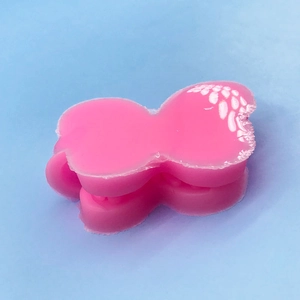 Pink butterfly hair claw clip with matte finish on light blue background top view
