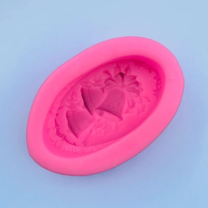 Macro detail of pink silicone mold with Christmas bell and holly leaf embossing