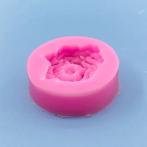 Pink silicone flower mold for DIY aromatherapy soap and candle making on blue background