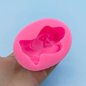 Hand holding pink 3D angel baby silicone mold for soap and baking on blue background