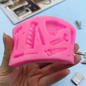 Pink silicone mold featuring miniature hardware tool shapes like saws and hammers