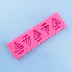 Detailed macro view of pink silicone mold with five Christmas tree shaped cavities for baking