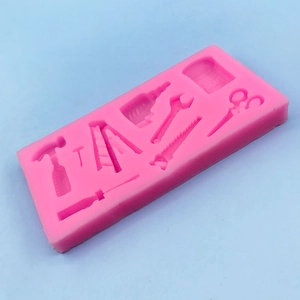 Pink silicone mold featuring miniature hardware tools like hammer, saw and ladder