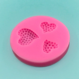 Pink silicone heart cookie mold with honeycomb texture on a blue background