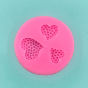 Detailed view of pink silicone mold with three textured heart shapes for DIY dessert making