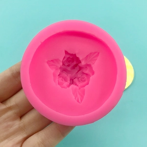 Pink silicone mold for baking with three rose and leaf patterns held in hand