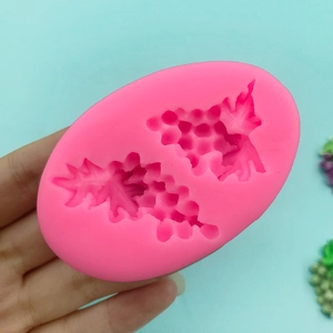 Pink silicone grape mold for chocolate and cake decorating on light blue background