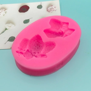 Pink silicone mold for strawberry shaped chocolate, fondant, and candles on a green surface